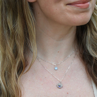 Someone wearing the Sterling Silver Purple Evil Eye Necklace with Paperclip Chain and the Sterling Silver Dainty Blue Evil Eye Necklace.