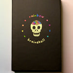 The Rainbow Brainskull Oracle Deck on a pink and blue background.