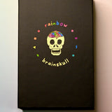 The Rainbow Brainskull Oracle Deck on a pink and blue background.