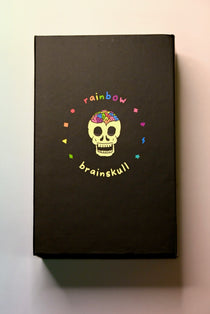 The Rainbow Brainskull Oracle Deck on a pink and blue background.