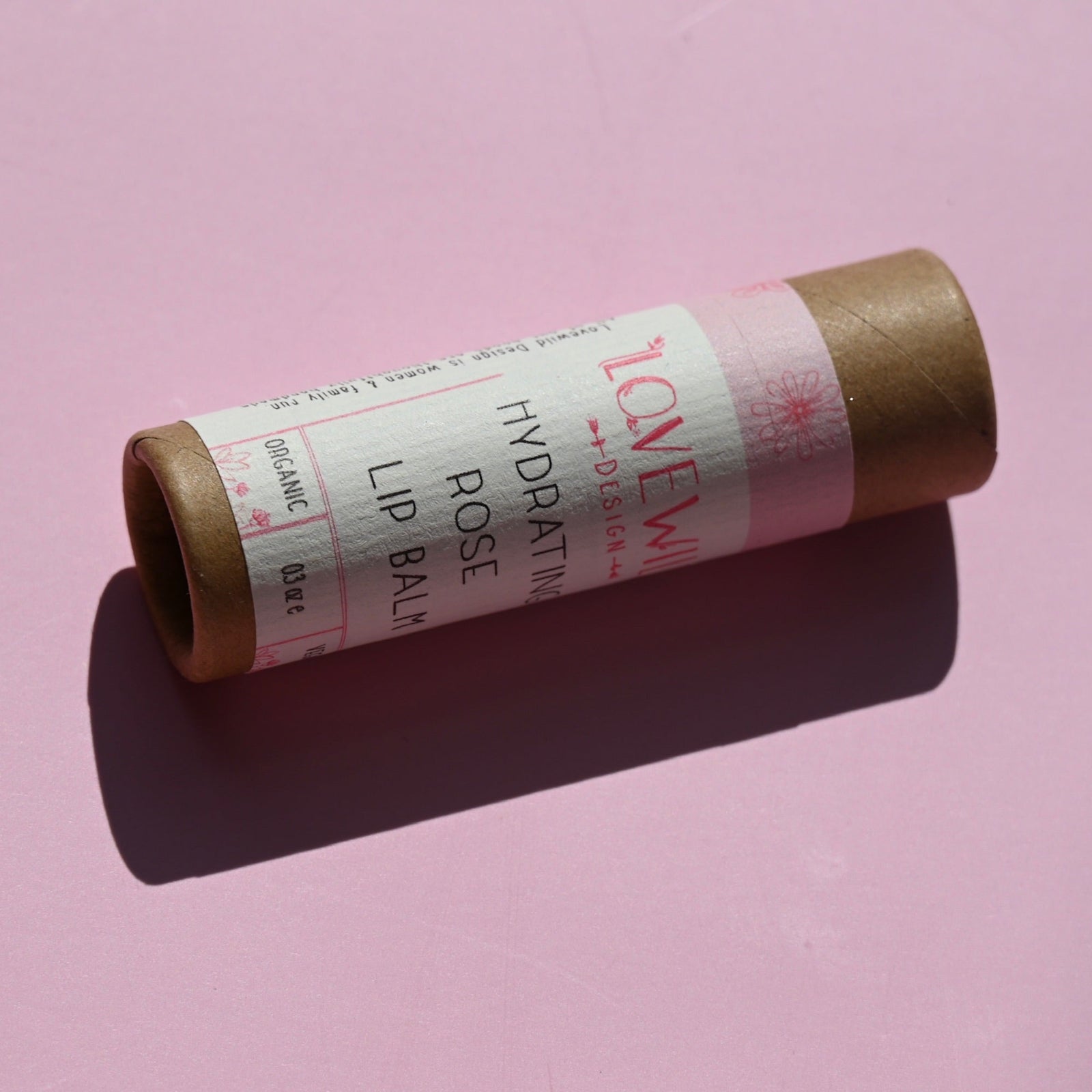 The Rose Lip Balm on a pink background.
