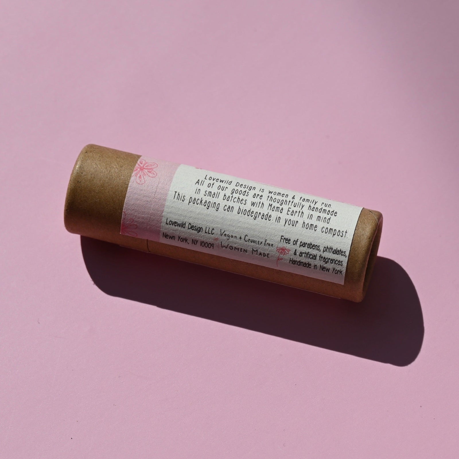 The side of the Rose Lip Balm on a pink background.