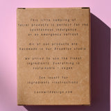 The back of the Mini Facial Kit on a pink background.