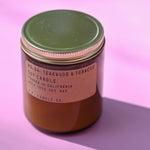 The P.F. Candle Co Teakwood & Tobacco - Standard Soy Candle on a pink background.