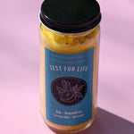 The Zest for Life Spell Candle with Herbs and Crystals on a pink background.