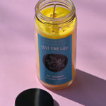 The Zest for Life Spell Candle with Herbs and Crystals on a pink background with its lid open and to the side.