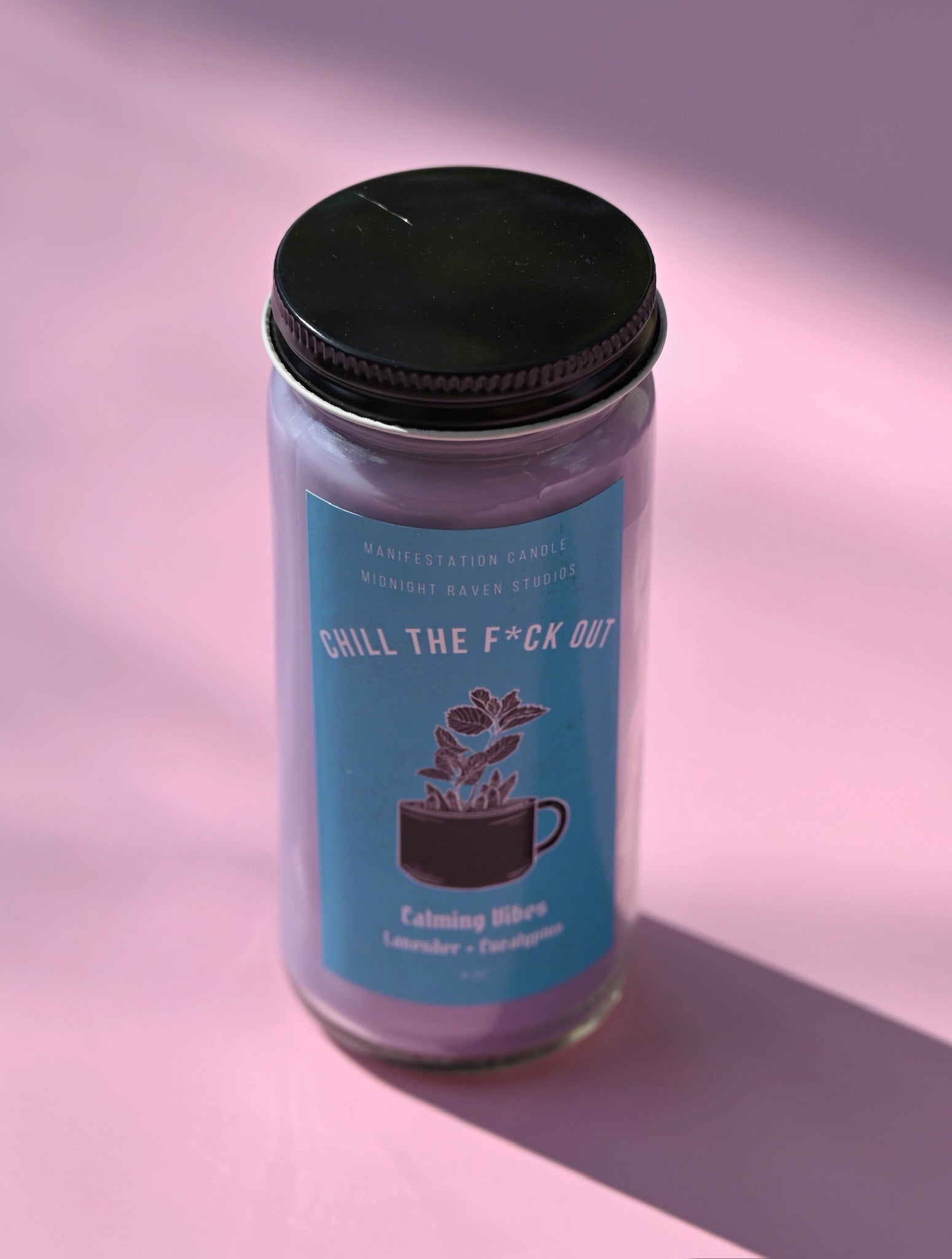 The Chill the F*ck Out Spell Candle with Herbs and Crystals on a pink background.