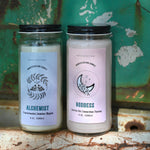 Two manifestation candles in front of a teal background and on a white rusty surface.