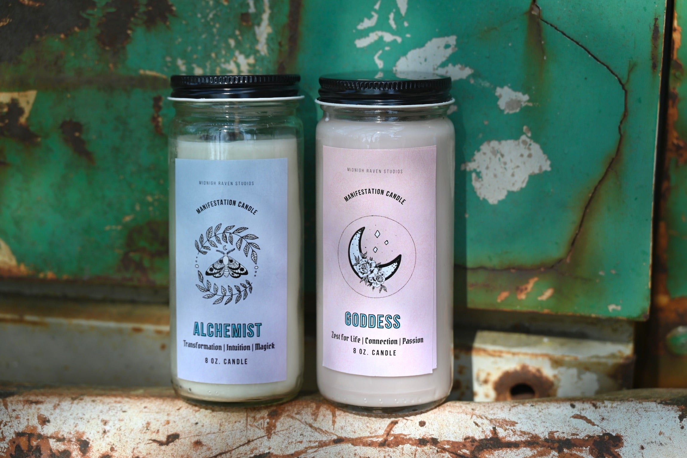 Two manifestation candles in front of a teal background and on a white rusty surface.
