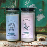 Two manifestation candles in front of a teal background and on a white rusty surface.
