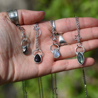 Someone holding all of the stainless steel celestial necklaces.