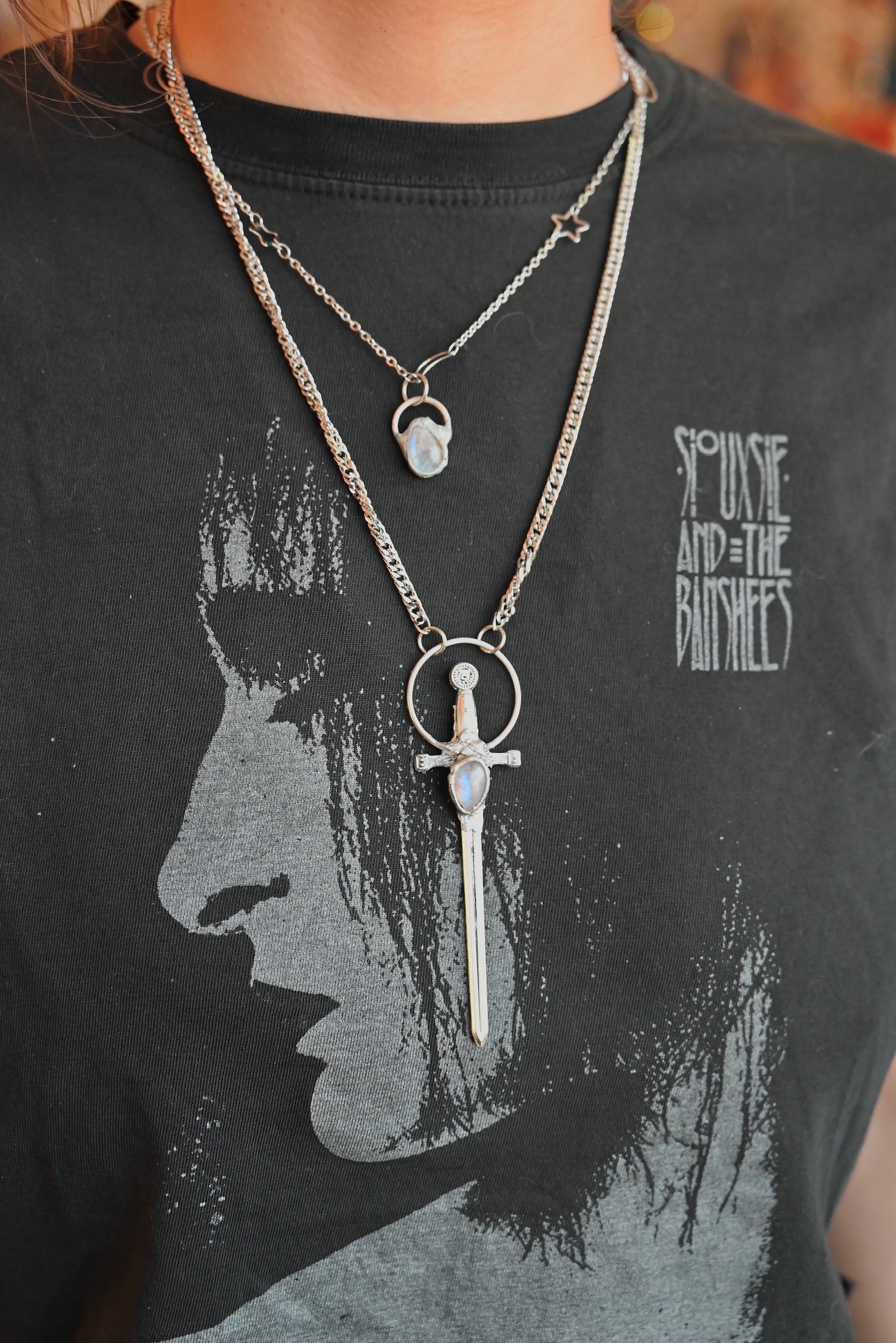 The Stainless Steel Moonstone Sword Necklace and Moonstone Sterling Silver Celestial Necklace being worn by someone.