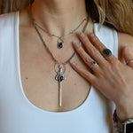 Someone wearing the Sterling Silver Garnet Sword Necklace and the Garnet Sterling Silver Celestial Necklace.