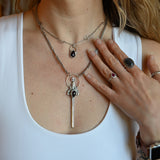 Someone wearing the Sterling Silver Garnet Sword Necklace and the Garnet Sterling Silver Celestial Necklace.