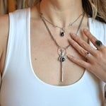 Someone wearing the Sterling Silver Garnet Sword Necklace and the Garnet Sterling Silver Celestial Necklace.