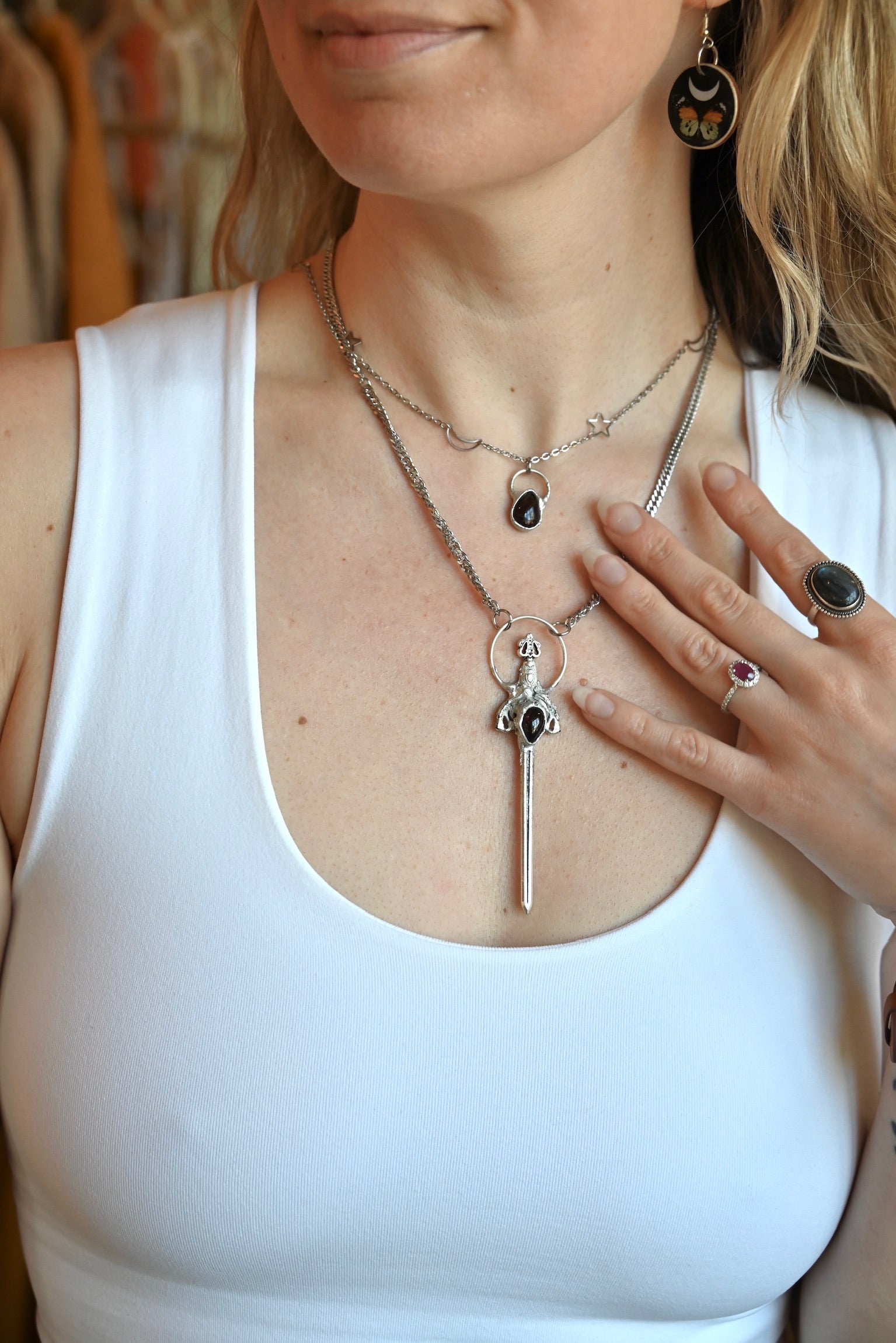 Someone wearing the Sterling Silver Garnet Sword Necklace and the Garnet Sterling Silver Celestial Necklace.