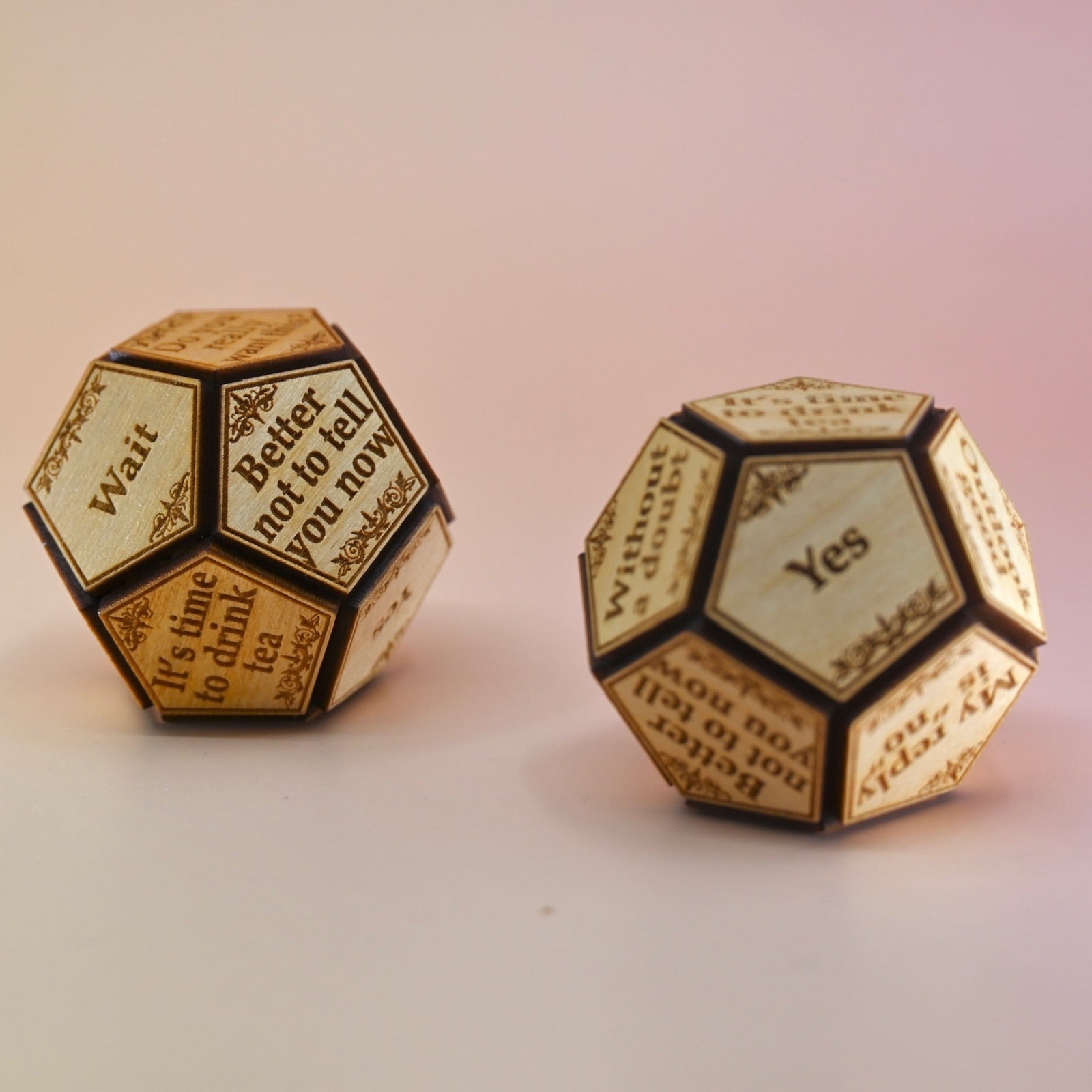 Two of the Twelve Sided Single Divination Die on a pink background.