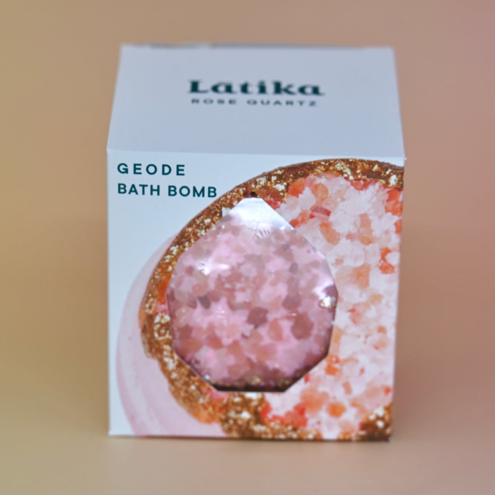The Rose Quartz Crystal Bath Bomb in its box on a pink background.