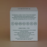 The back of the box of the Latika Beauty bath bomb on a pink background.