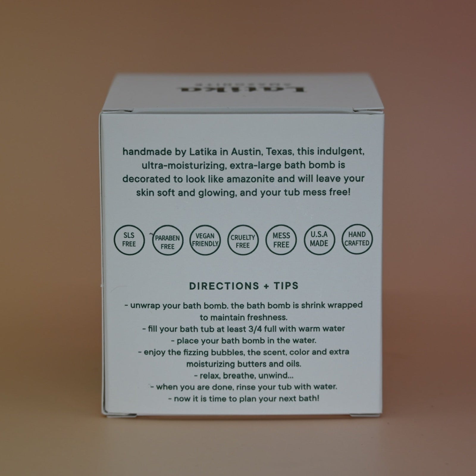 The back of the box of the Latika Beauty bath bomb on a pink background.