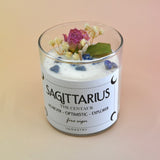 The Sagittarius Zodiac Crystal Candle on a peach colored background.