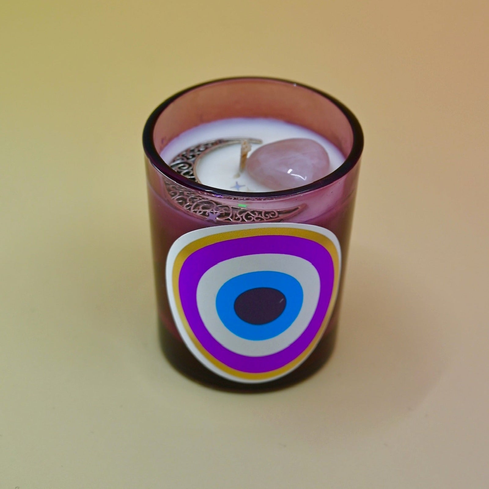 The Purple Evil Eye Moon Votive Candle on a yellow background.