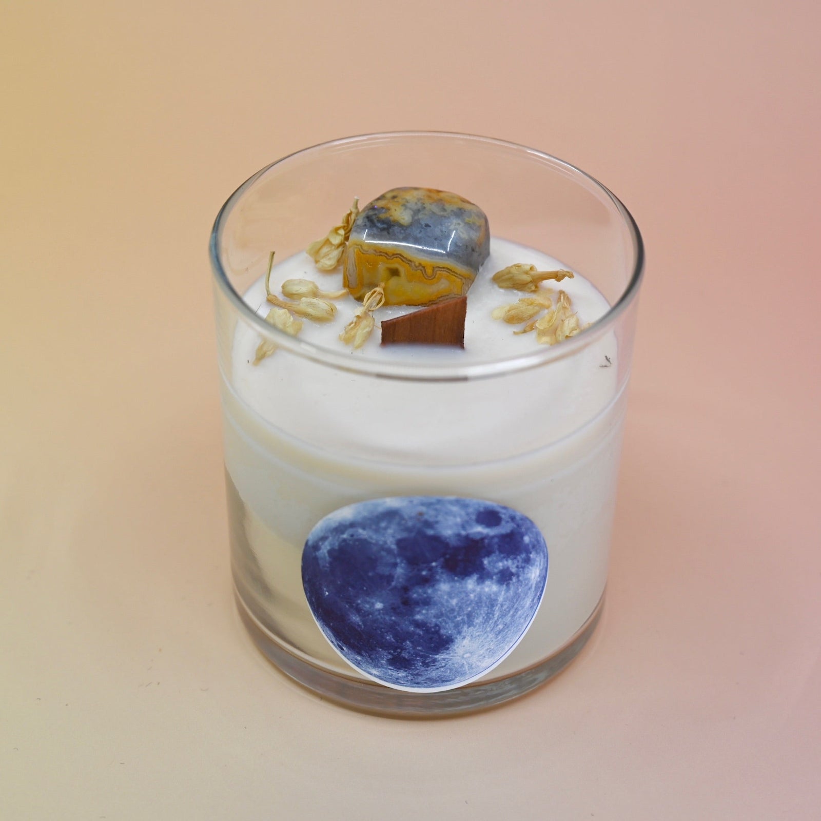 The Moonchild Crystal Candle on a pink background.