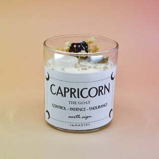 The Capricorn Zodiac Crystal Candle on a peach colored background.