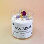 The Aquarius Zodiac Crystal Candle on a peach colored background.