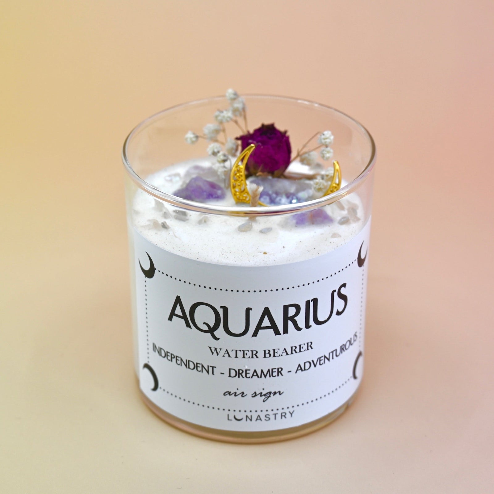 The Aquarius Zodiac Crystal Candle on a peach colored background.