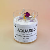 The Aquarius Zodiac Crystal Candle on a peach colored background.