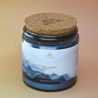 The Moons Ritual Candle on a pink and yellow background with the cork lid on.