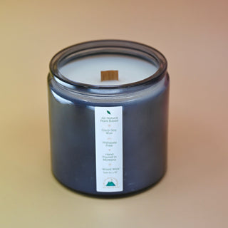The Moons Ritual Candle on a pink and yellow background with the back label showing and cork lid off.