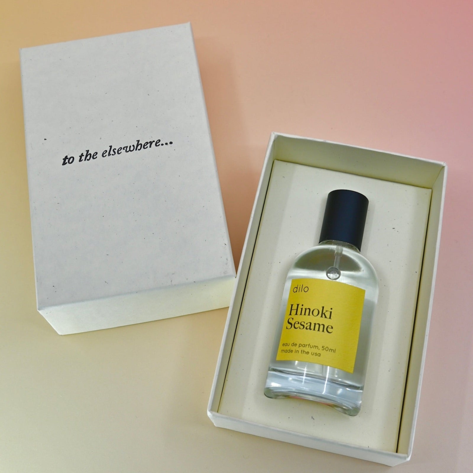 The Hinoki Sesame 50ml Unisex Eau de Parfum on a pink background in its box.