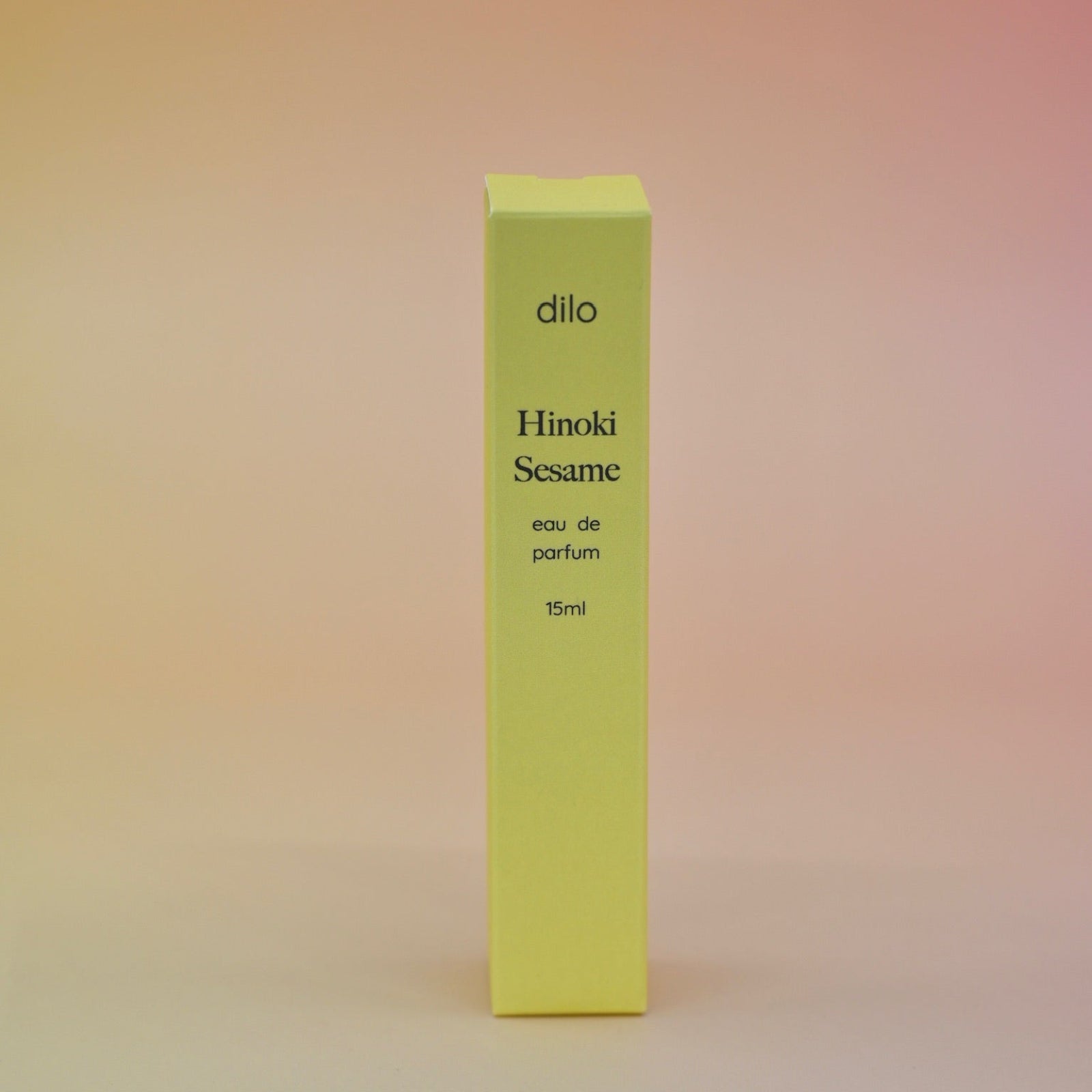 The box of the Hinoki Sesame 5ml Unisex Eau de Parfum Travel Sprayer on a pink and yellow background.