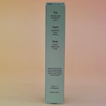The back of the box of the Desert Kush 15ml Unisex Eau de Parfum Travel Sprayer on alight pink background.