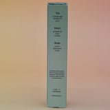 The back of the box of the Desert Kush 15ml Unisex Eau de Parfum Travel Sprayer on alight pink background.