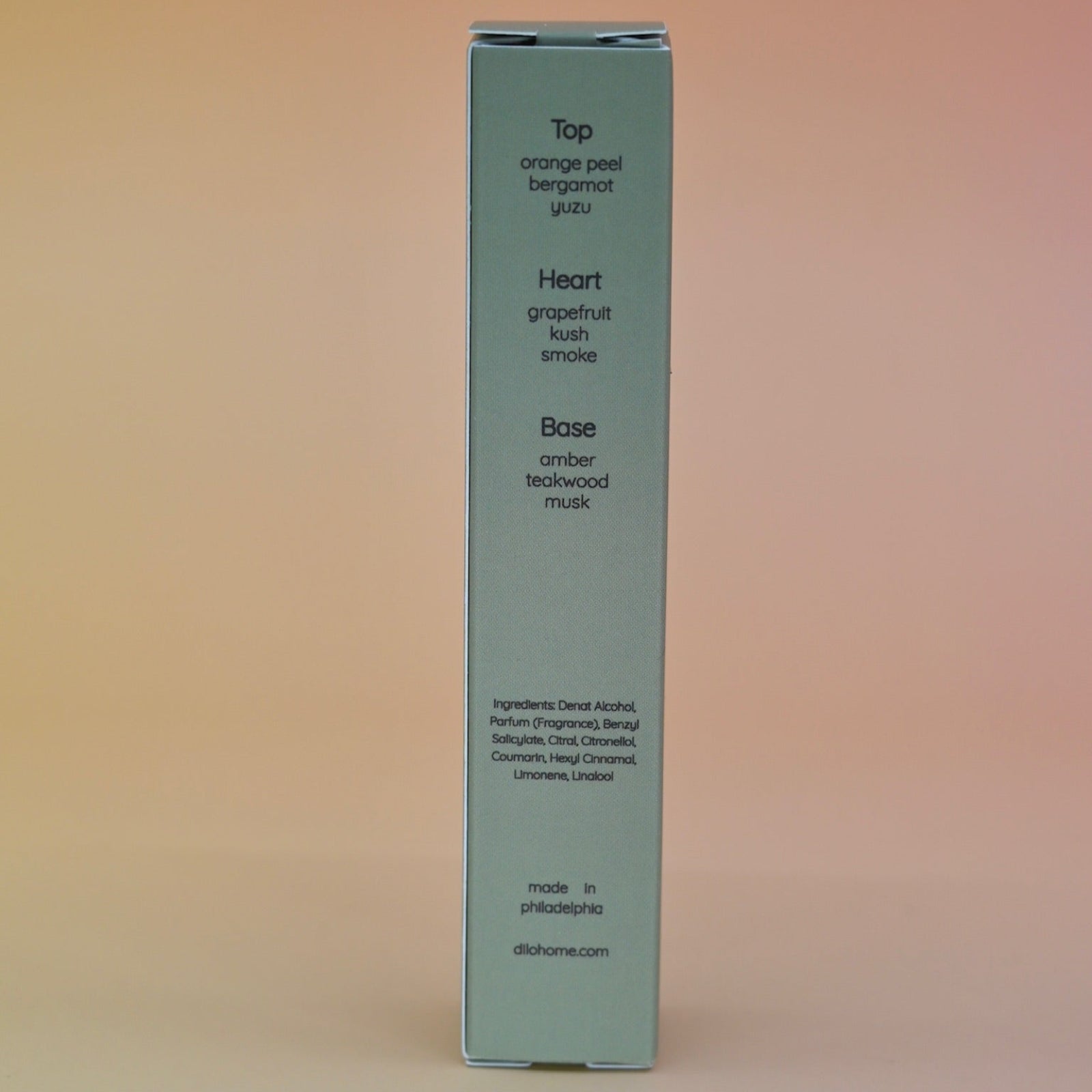 The back of the box of the Desert Kush 15ml Unisex Eau de Parfum Travel Sprayer on alight pink background.