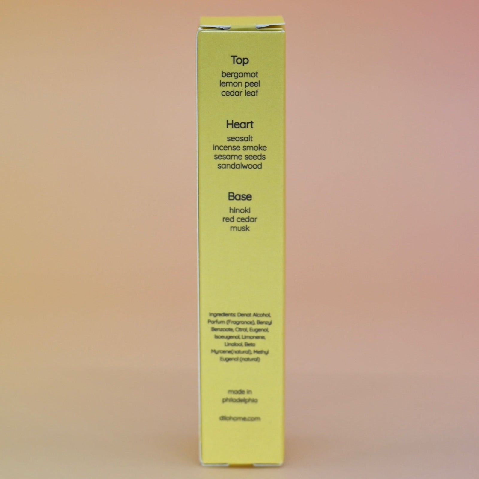 The back of the box of the Hinoki Sesame 5ml Unisex Eau de Parfum Travel Sprayer on a pink and yellow background.