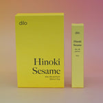 The boxes of the Hinoki Sesame 5ml Unisex Eau de Parfum regular sized bottle and the Travel Sprayer on a pink.