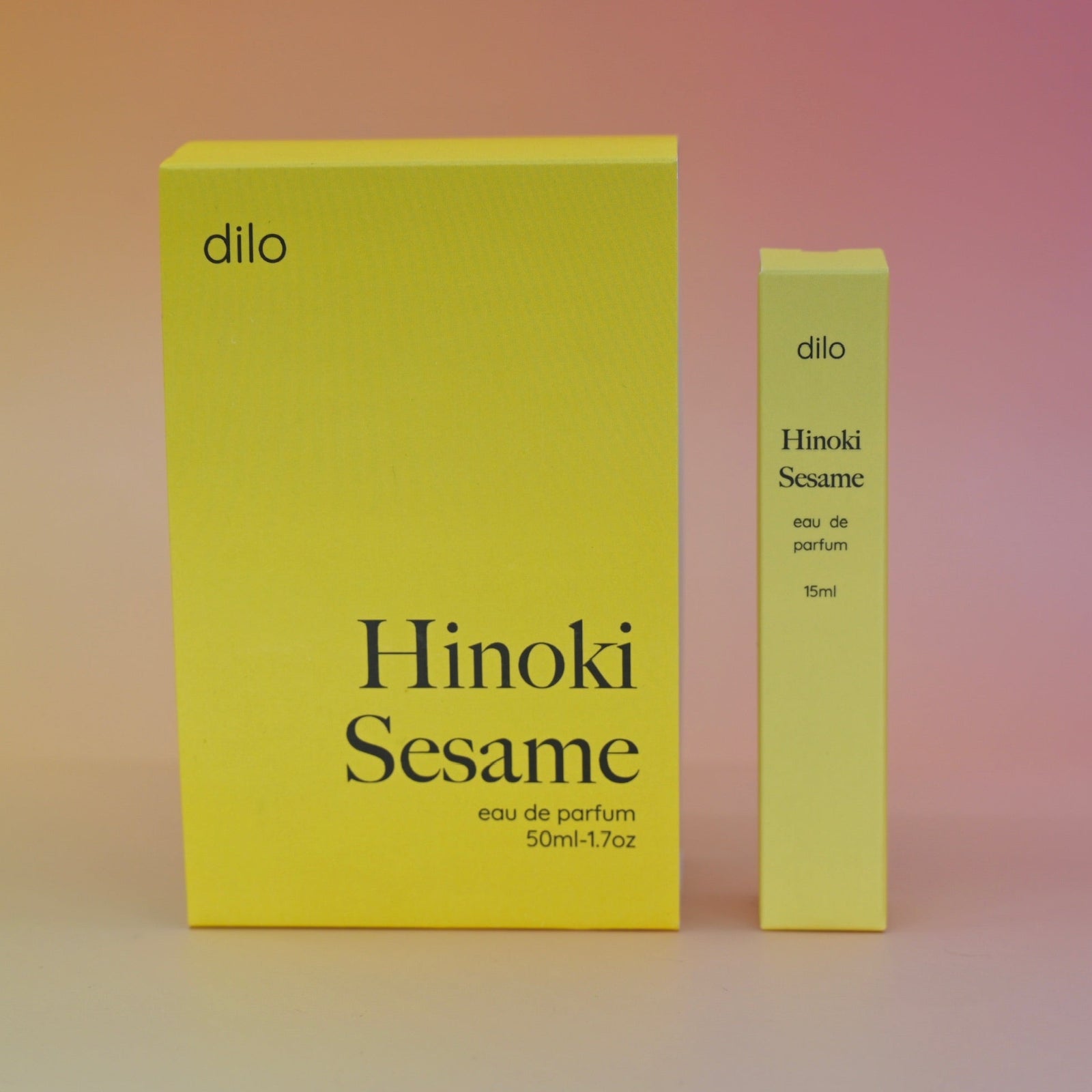 The boxes of the Hinoki Sesame 5ml Unisex Eau de Parfum regular sized bottle and the Travel Sprayer on a pink.