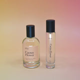 The bottle of the Cactus Flower 15ml Unisex Eau de Parfum Travel Sprayer and regular sized bottle on a pink background.