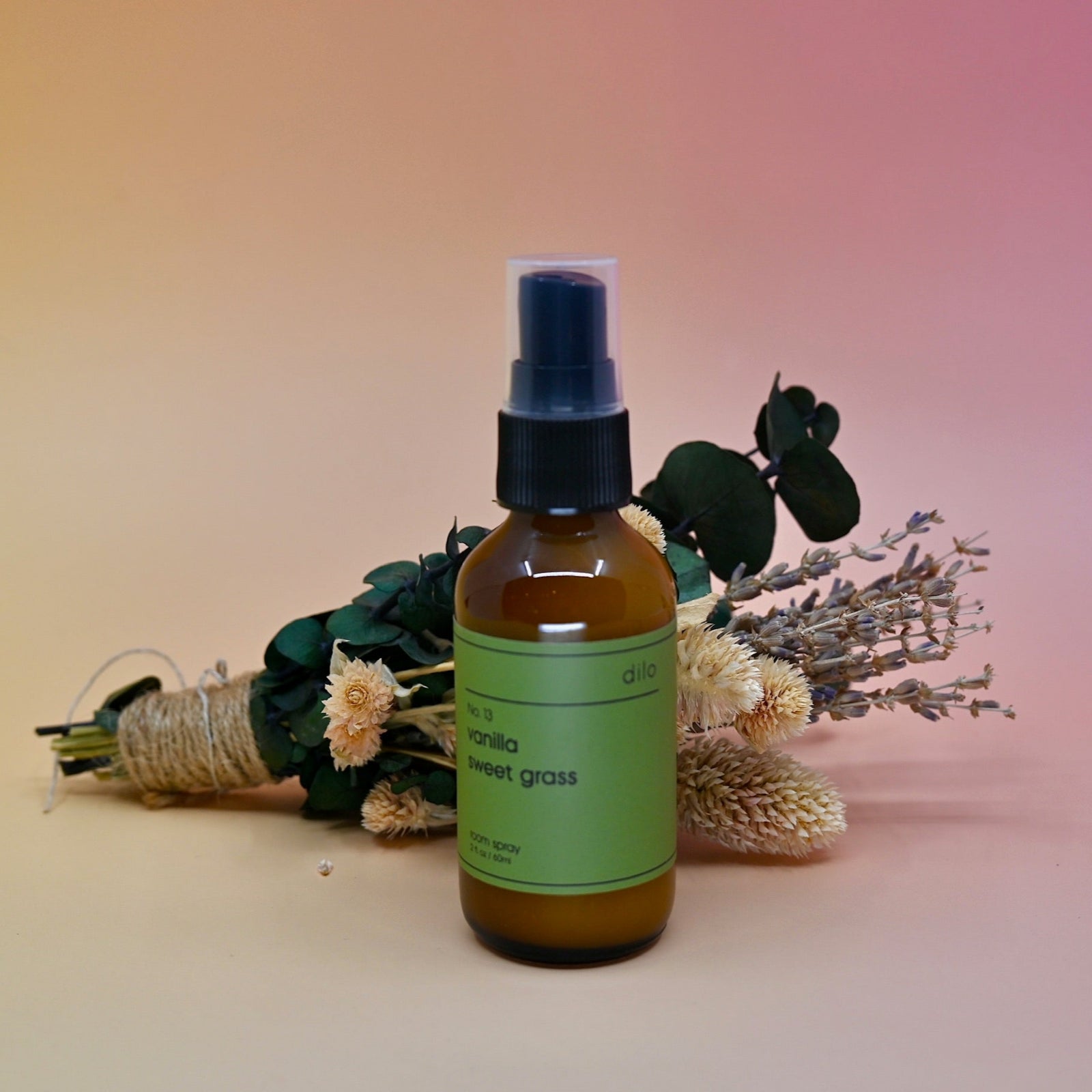 The No. 13 Vanilla Sweet Grass Room Spray in front of a dried flower bundle on a pink background.