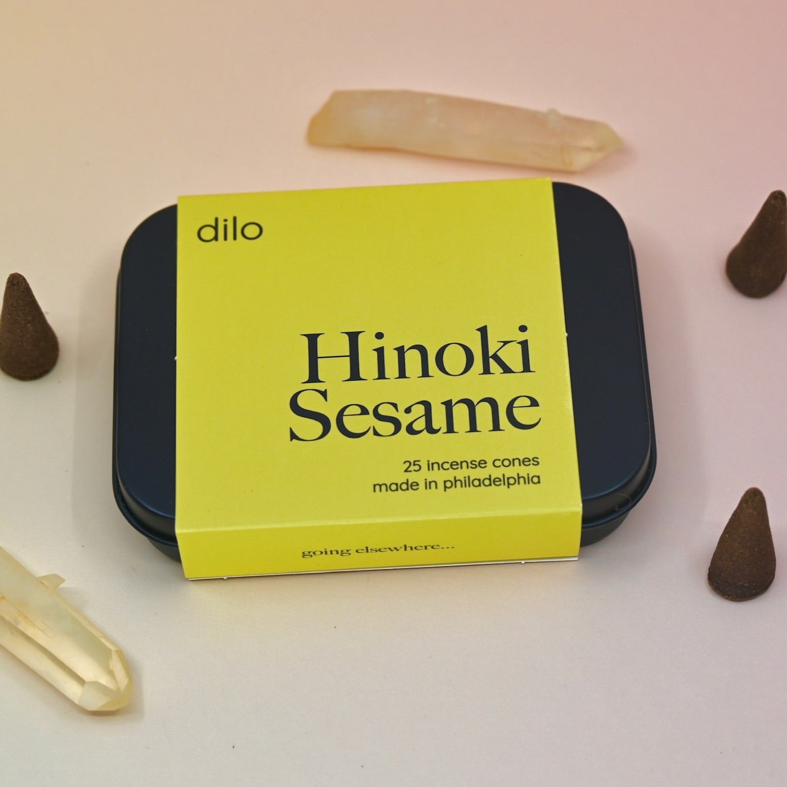 The Hinoki Sesame Cone Incense on a light pink background surrounded by incense cones and crystals.