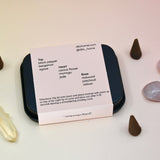 The  back of the Cactus Flower Incense Cones - Pack of 25 tin on a light pink background surrounded by crystals and incense cones.