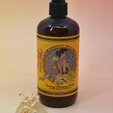 The Essential Oil Cleansing Hand & Body Wash with a crystal in front of it on a light pink background.