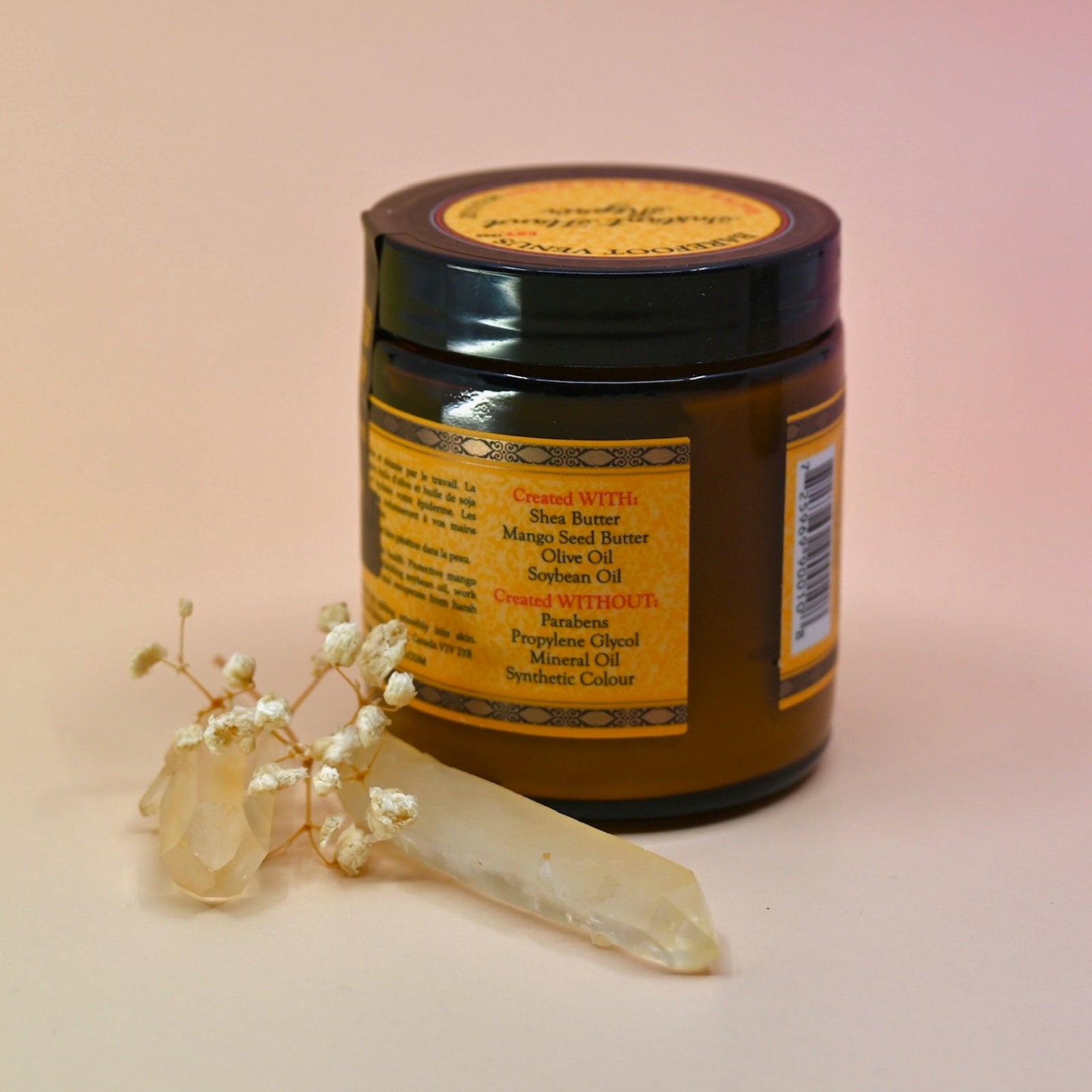 The back of the Essential Oil Instant Hand Repair Balm with a crystal in front of it on a light pink background.