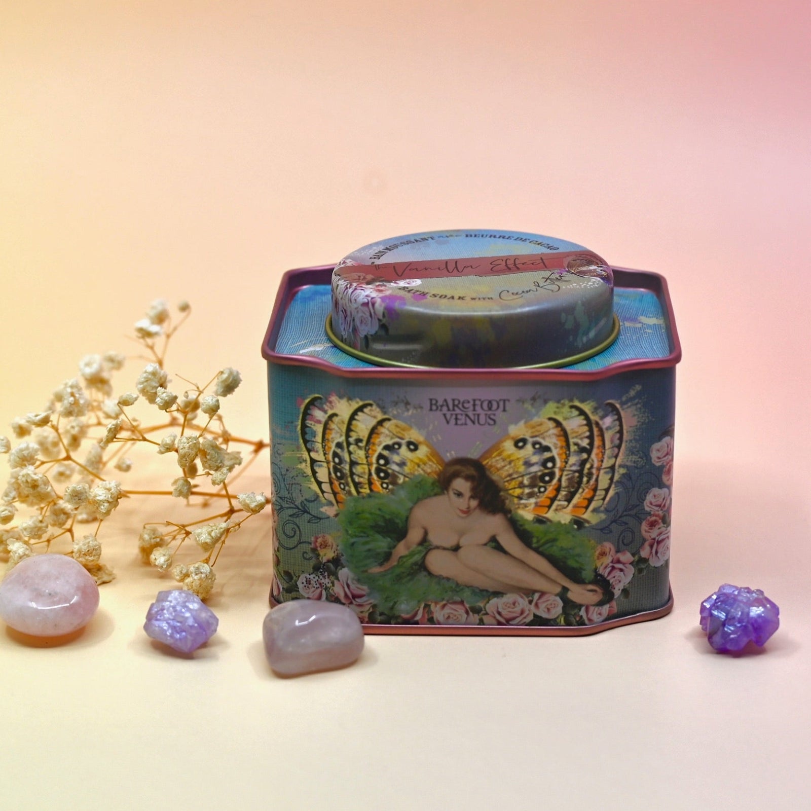 The Vanilla Effect Bath Soak surrounded by crystals and a dried flower on a light pink background.