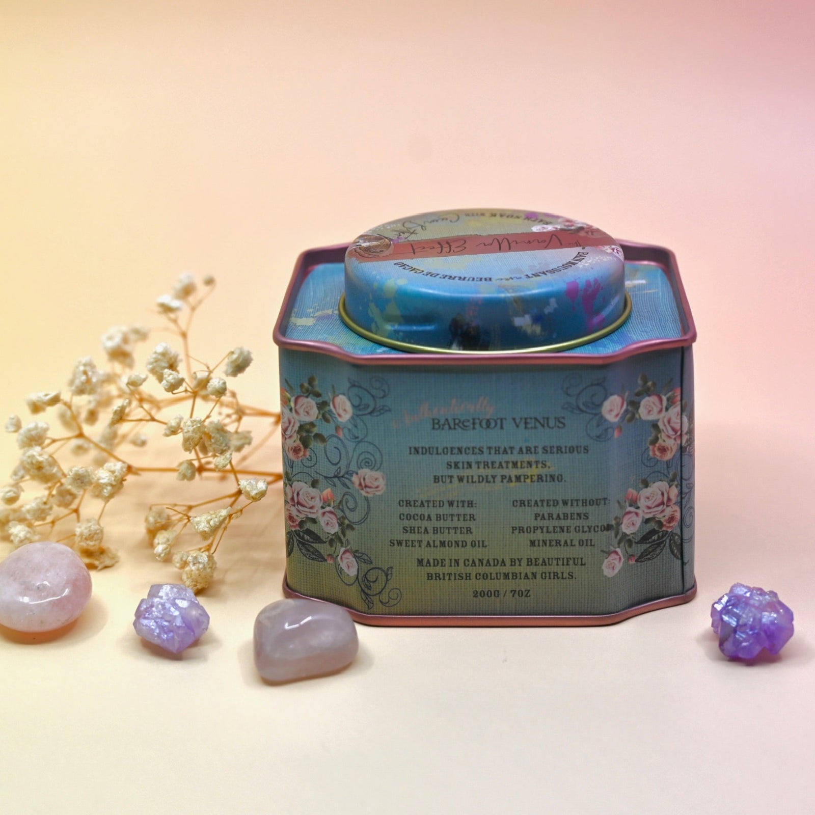 The back of the Vanilla Effect Bath Soak surrounded by crystals and a dried flower on a light pink background.