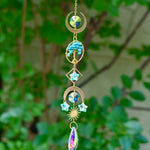 The turquoise Tree of Life Crystal Suncatcher with greenery in the background.